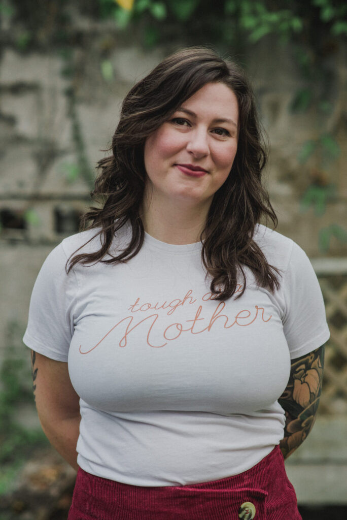 Kellie Britch, a birth and postpartum doula, smiling and wearing a "tough as Mother" t-shirt.