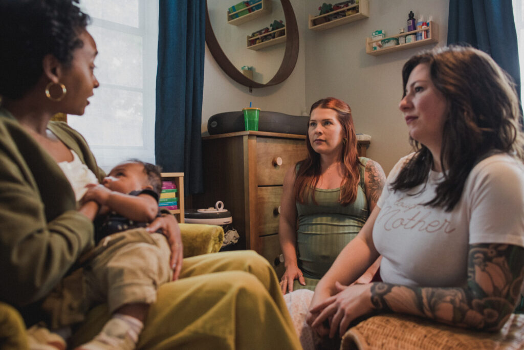 Kellie Britch sitting in a room with two other women, providing support and guidance during a postpartum session.