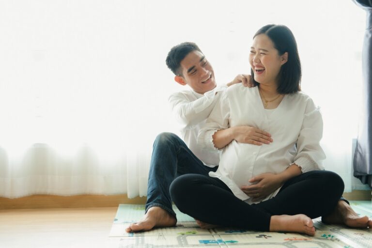 A pregnant couple sitting on the floor, sharing thoughts and preparing for their upcoming journey into parenthood.